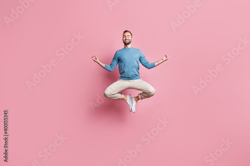 Full length photo of strong adorable young man dressed blue sweater jumping high practicing yoga isolated pink color background