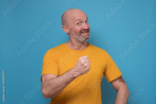 Happy successful mature man showing fist. He has done all his tasks and is satisfied with results.