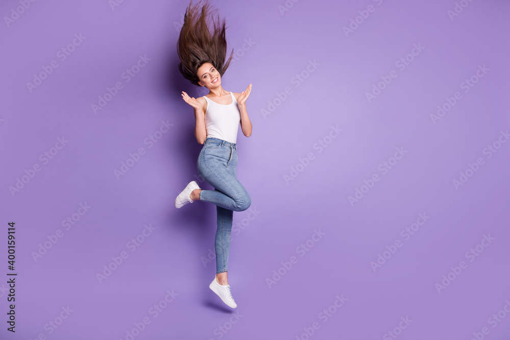 Fototapeta premium Full size photo of slim happy brown haired woman jump up wear jeans raise palms isolated on purple color background