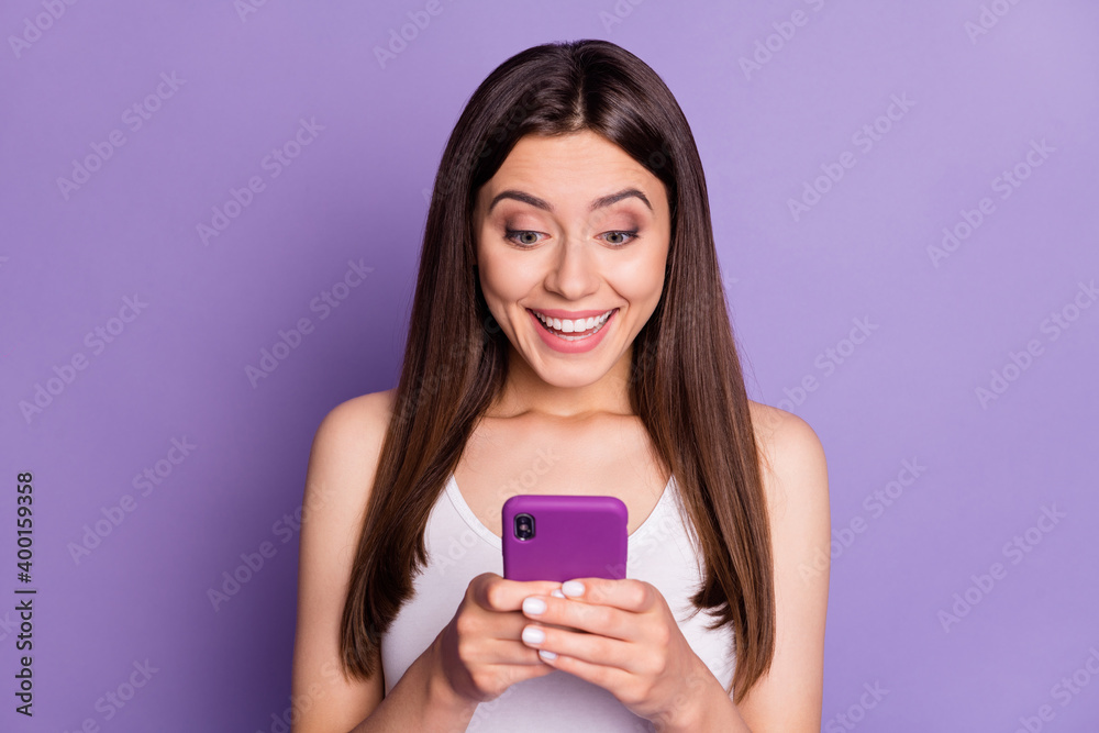 Photo of impressed brown haired young woman wear white singlet good news on media sale isolated on violet color background Photo of impressed brown haired young woman wear white singlet good news on media sale isolated on violet color background