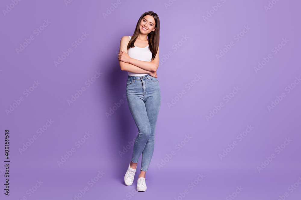 Full body photo of cheerful joyful girl good mood smile wear white singlet jeans isolated on purple color background Full body photo of cheerful joyful girl good mood smile wear white singlet jeans isolated on purple color background