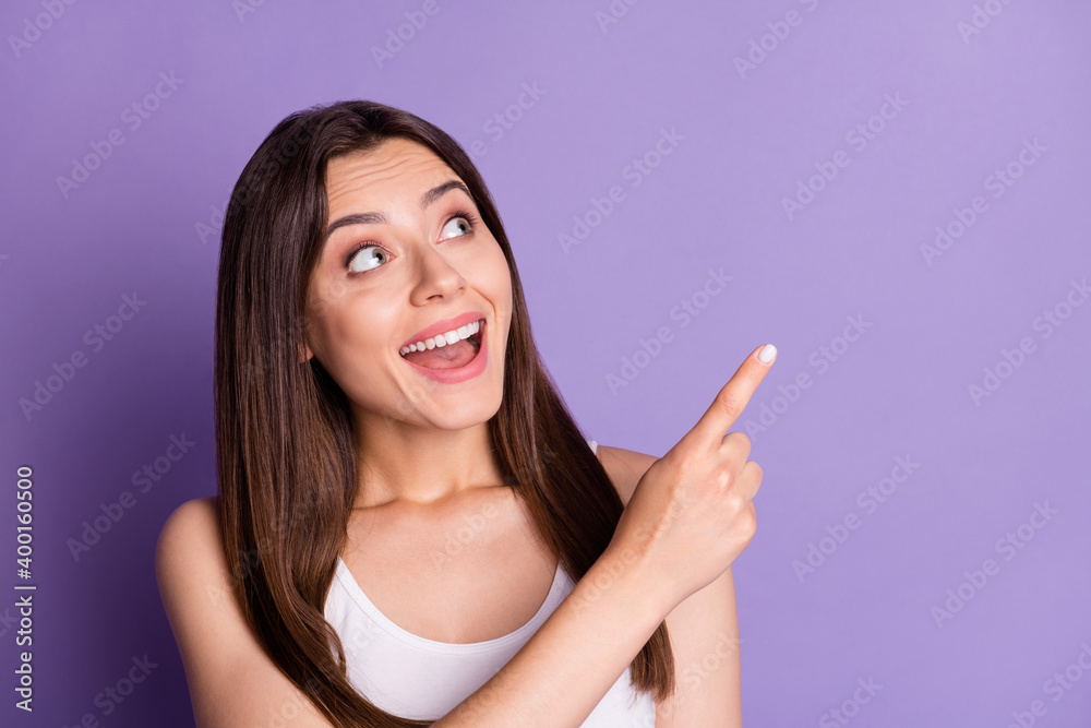 Photo of charming cute young woman wear casual white outfit looking pointing one finger empty space isolated violet color background Photo of charming cute young woman wear casual white outfit looking pointing one finger empty space isolated violet color background