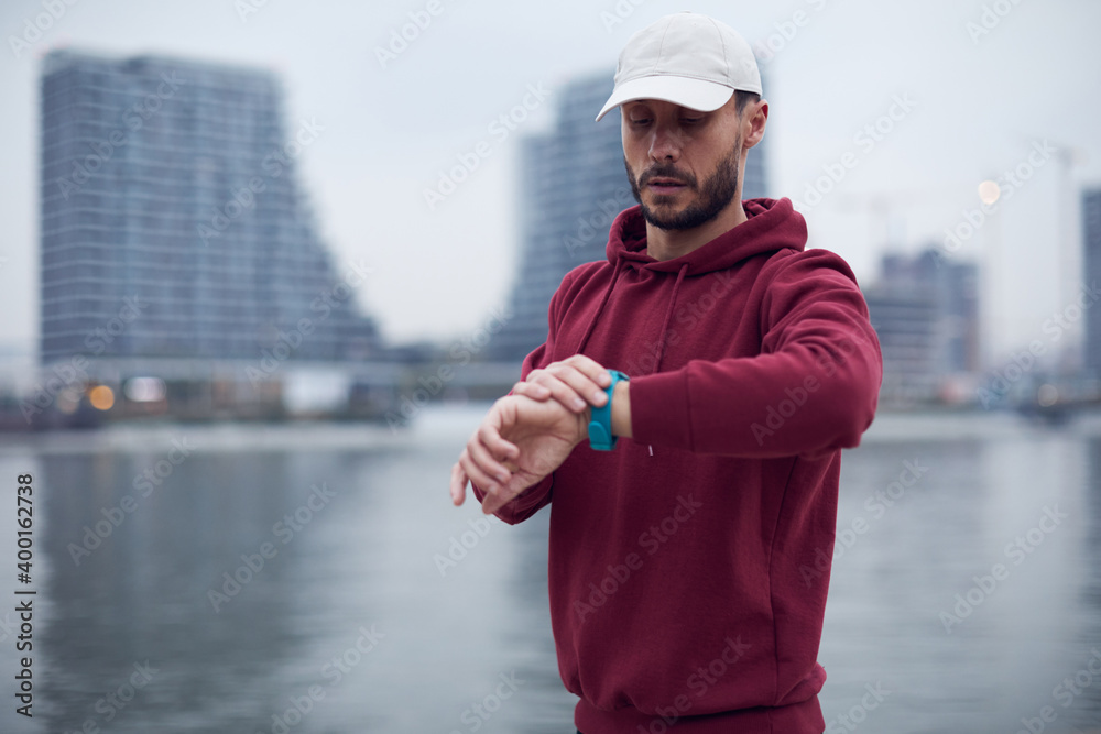 Athletic sporty man training in hoodie sweatshirt in urban city park near the river. Athletic sporty man training in hoodie sweatshirt in urban city park near the river.