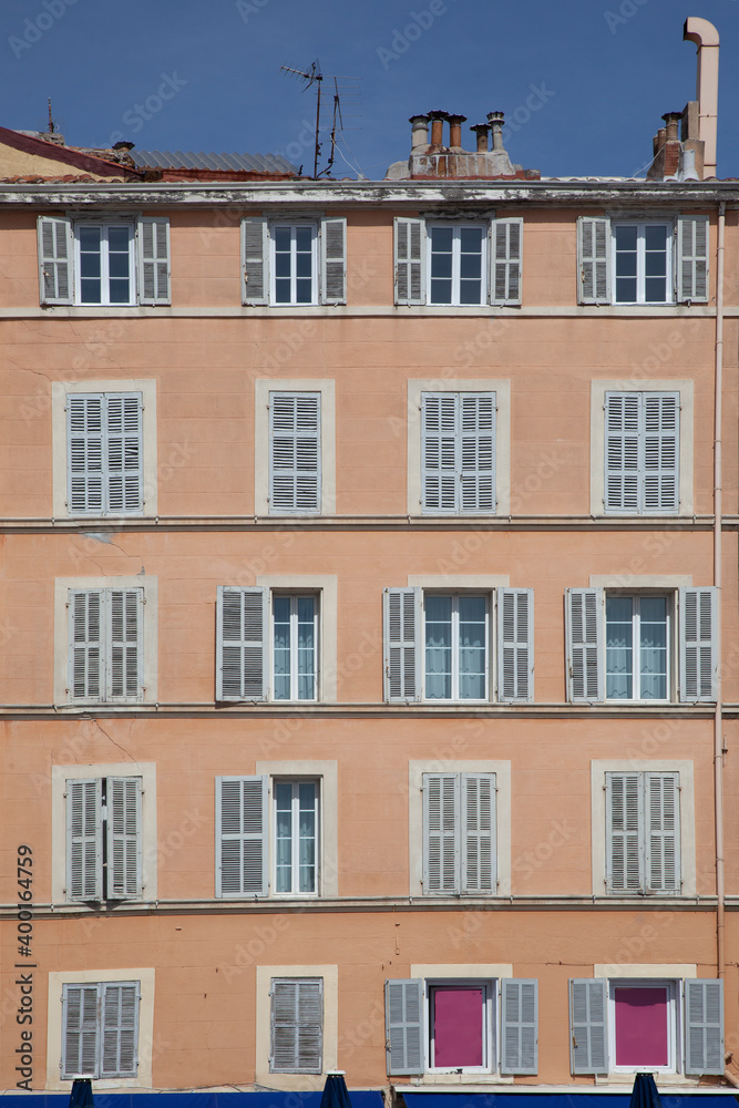 typical facade of an old hotel with open and closed shutters in traditional style