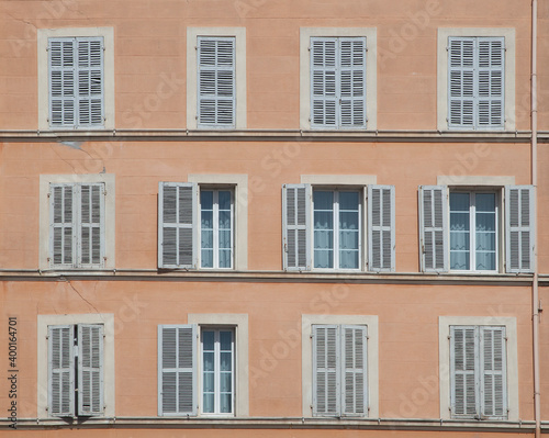 typical facade of an old hotel with open and closed shutters in traditional style