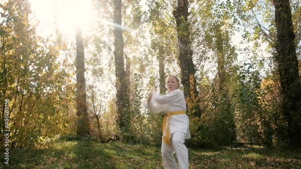 teenager girl 12 years old is engaged in karate outdoors in the park. Healthy lifestyle concept. playing sports. martial arts. Judo, Jiujitsu. bold, strong. practicing various stances and exercises. teenager girl 12 years old is engaged in karate outdoors in the park. Healthy lifestyle concept. playing sports. martial arts. Judo, Jiujitsu. bold, strong. practicing various stances and exercises.
