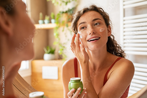 Woman applying moisturiser on face during morning routine photo