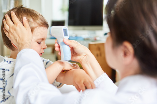 Kinderarzt beim Fieber messen mit Stirnthermometer