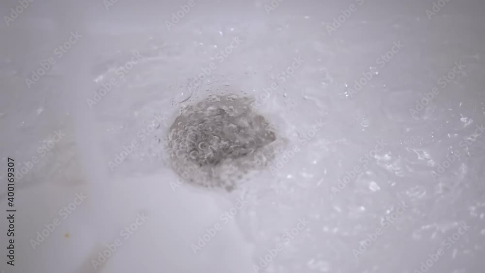 Drain Hole in Sink is Clogged. Bubbling Water Pours Into a Clogged White Sink