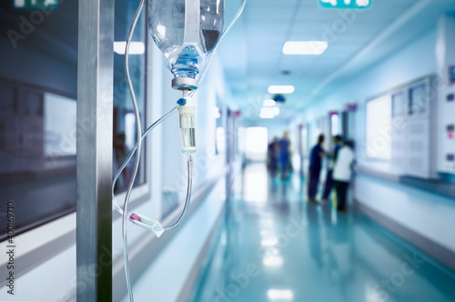 Intravenous drip in the hospital corridor against the blurred figure of medical staff
