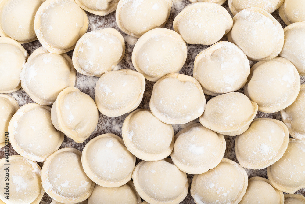 top view of many frozen Pelmeni (russian dumplings filled with minced meat) on wooden board top view of many frozen Pelmeni (russian dumplings filled with minced meat) on wooden board