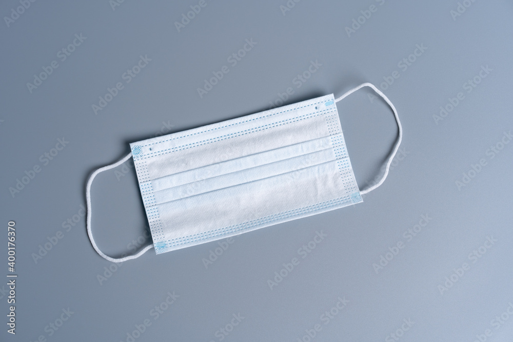 Surgical mask with rubber ear straps. Typical 3-ply surgical mask to cover the mouth and nose. Procedure mask from bacteria. Protection concept. Surgical mask with rubber ear straps. Typical 3-ply surgical mask to cover the mouth and nose. Procedure mask from bacteria. Protection concept.