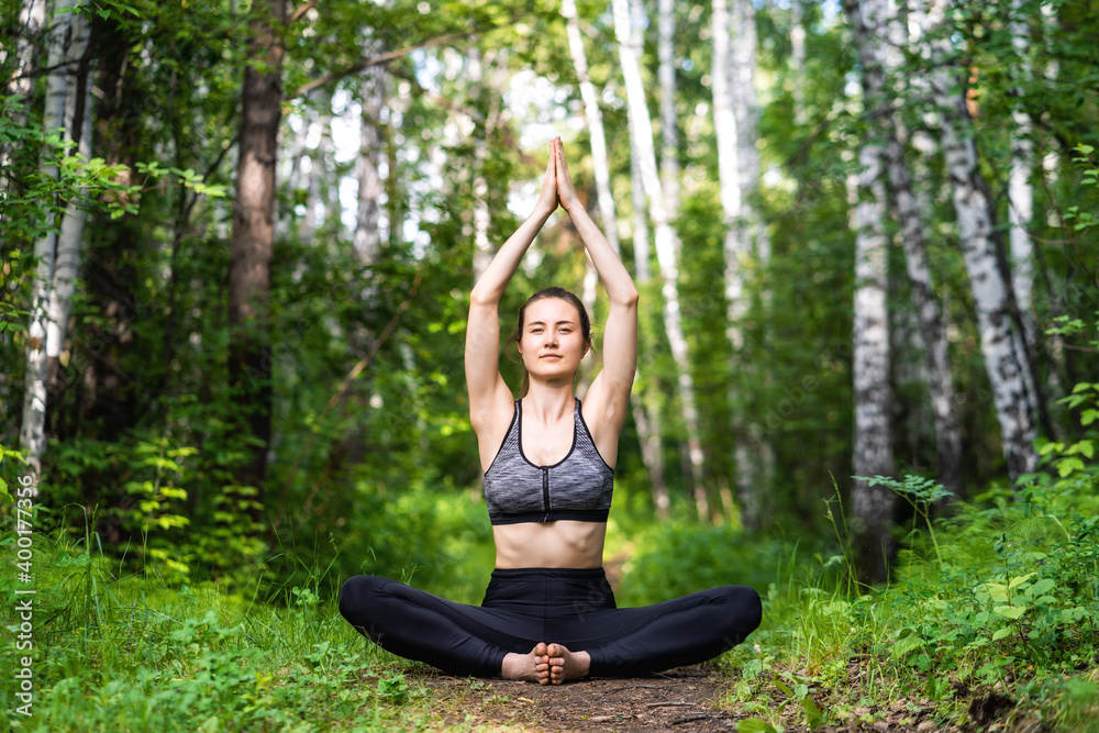 Girl sitting in a bound angle pose in a summer forest