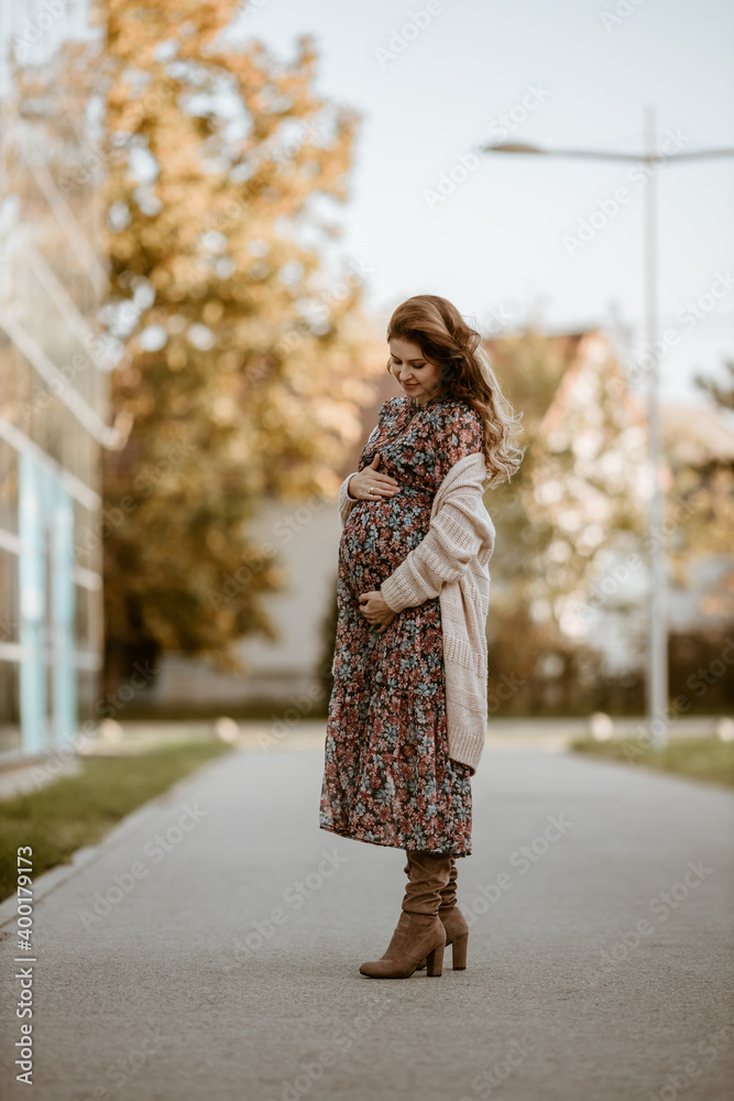 Pregnant woman in dress walking outdoor 