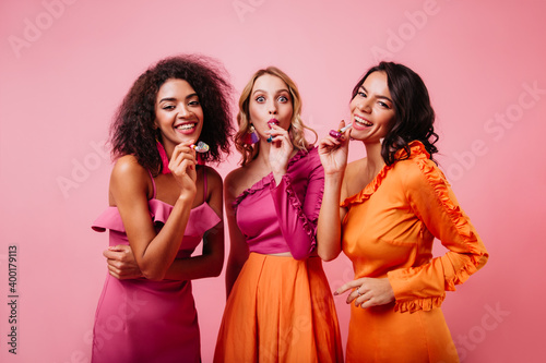 Horizontal portrait of three international friends. Studio photo of young women having fun at party.
