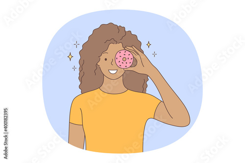 Unhealthy eating, fast and junk food, calories concept. Young positive girl cartoon character standing and holding fast food sugar fat donut over eye. Overweight, snack, lifestyle, harmful eating