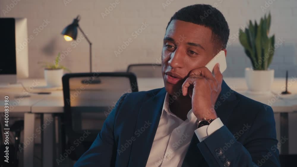 young african american businessman talking on smartphone at night in office young african american businessman talking on smartphone at night in office