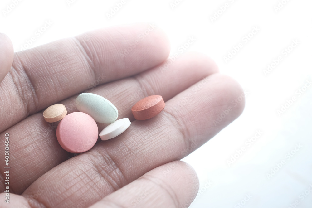 close up of colorful pills on hand isolated on white 