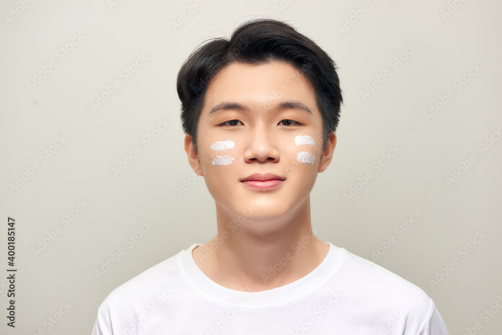 Portrait of young handsome man applying cream lotion on face - isolated on white. Portrait of young handsome man applying cream lotion on face - isolated on white.