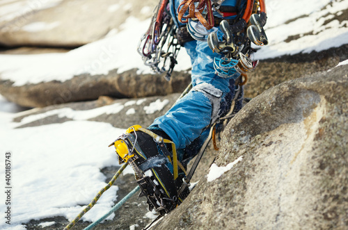 Crampons on high-altitude boots of a mountaineer during a winter ascent in cold conditions in the mountains, close-up.