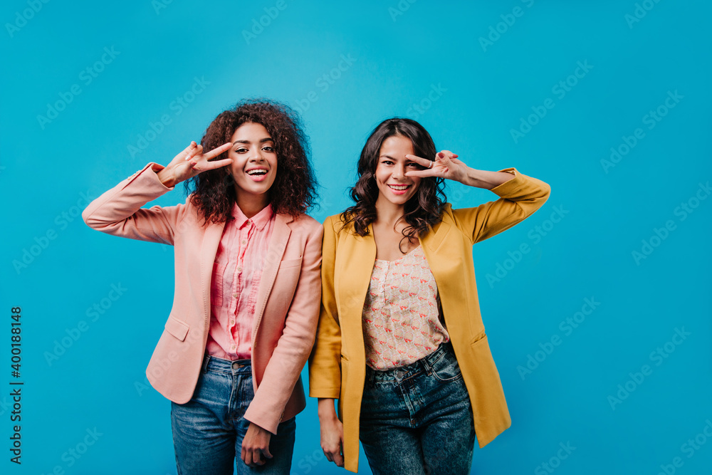 Two inspired girls having fun while shooting. Studio portrait of mixed race women. Two inspired girls having fun while shooting. Studio portrait of mixed race women.