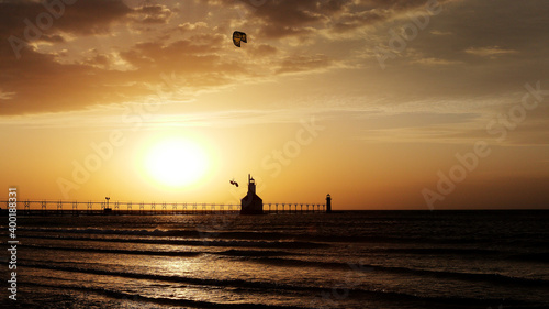 Kite boarder in the air at sunset by a lighthouse
