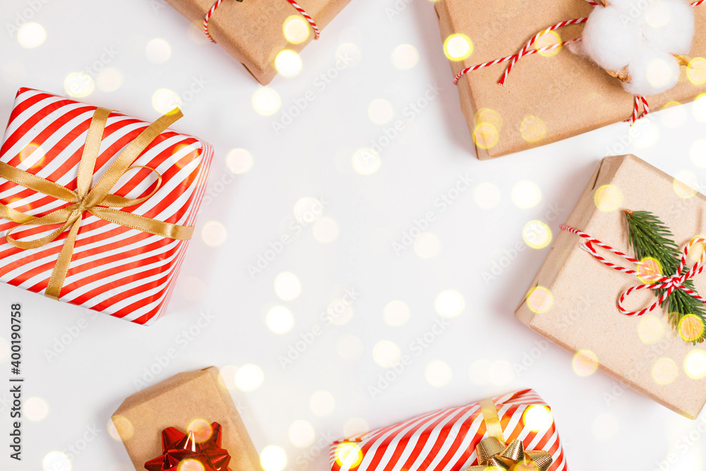 Fototapeta premium Happy New Year horizontal composition. Christmas striped design gifts box, golden and red bow, confetti glitter light on white background with copy space. Flat lay, top view