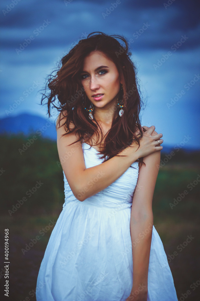 A beautiful woman stands in a field.The wind blows the girl's hair.cloudy day.The concept of beauty and ecology. A beautiful woman stands in a field.The wind blows the girl's hair.cloudy day.The concept of beauty and ecology.