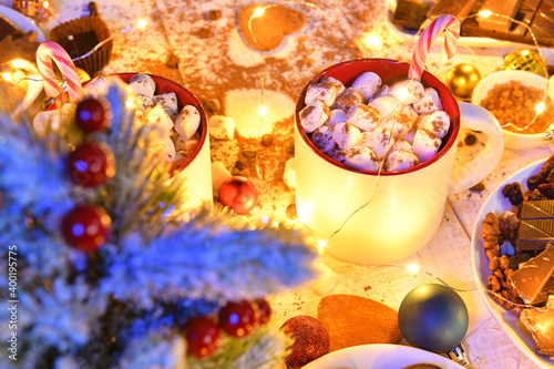 sweet food top view background for merry christmas or new year holiday decoration with night illumination - chocolate candies  tangerines  cookies  marshmallow and cocoa latte on white wood