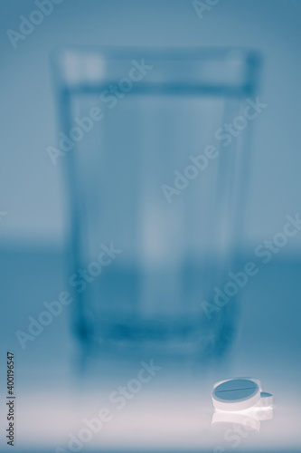 glass of clean water and a tablet on a light background.