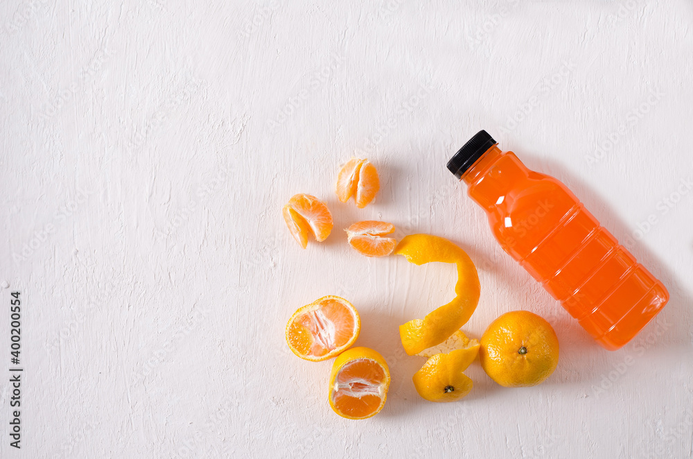 Fresh tangerines fruits and tangerine juice in a bottle on a structural light background. Food background with flat lay and copy space