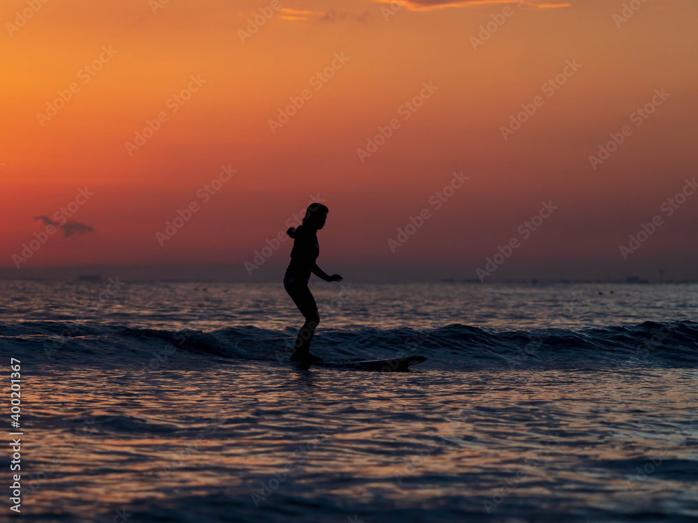 person surfboard on the beach at sunset