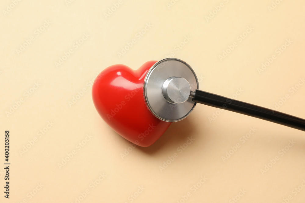 Black stethoscope and heart on beige background Black stethoscope and heart on beige background