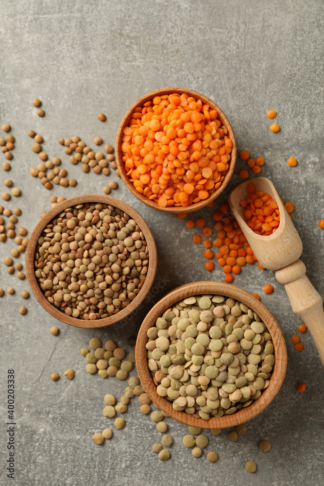 Scoop and bowls with different legumes on gray background Scoop and bowls with different legumes on gray background