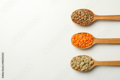 Spoons with different legumes on white background, space for text