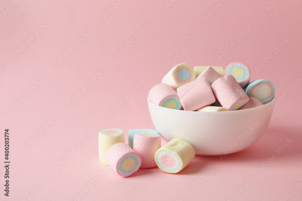 Bowl with marshmallow on pink background, space for text