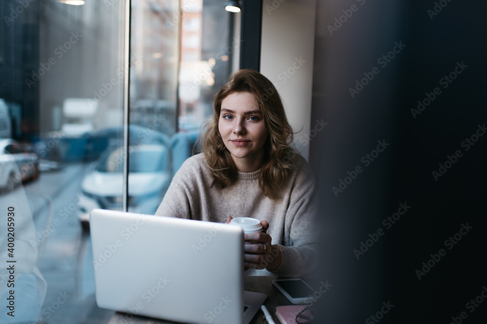 Positive young female manager drinking coffee during work on laptop Positive young female manager drinking coffee during work on laptop