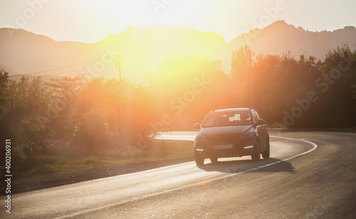 Car illuminated by sunlight moves on a bend in the road © Yuri Bizgaimer
