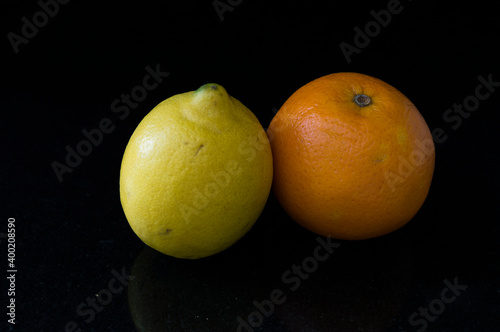 A lemon and an orange with black background