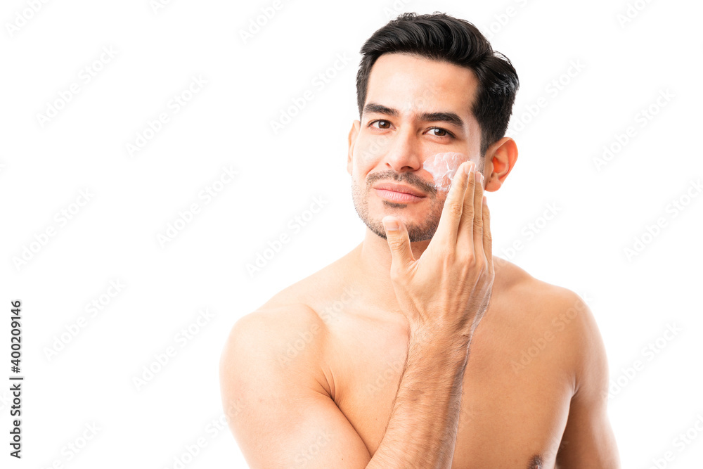 Fototapeta premium Young man applying moisturizer cream