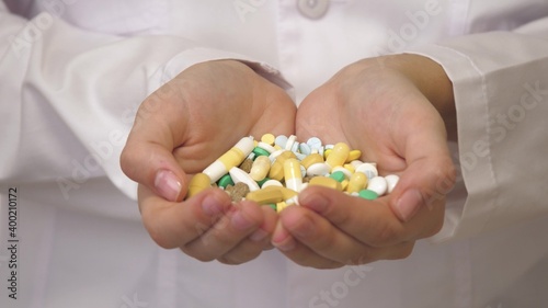Medicines in the hands of a medical professional in a white coat. Medicines for diseases for health. Multi-colored capsules deprisants. Close-up