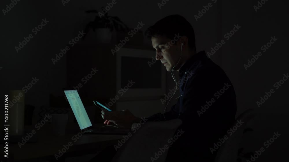 Young man working at home at night with headphones Sending an audio message. Living for working. Slave concept