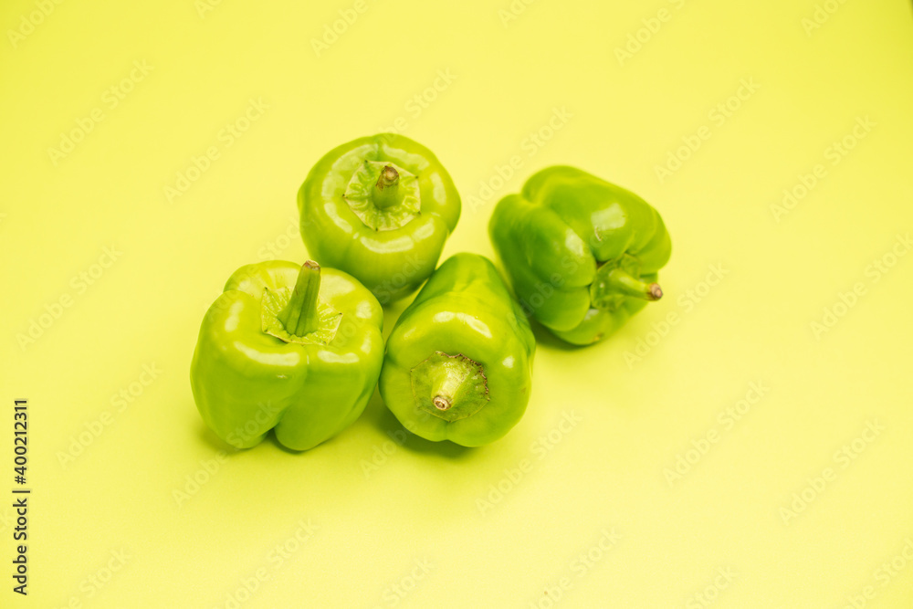 Overhead view of green fresh peppers necessary for cooking on yellow background Overhead view of green fresh peppers necessary for cooking on yellow background