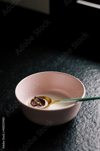 Luxurious green and gold spoon with cereals on a pink bowl full of milk on the kitchen counter