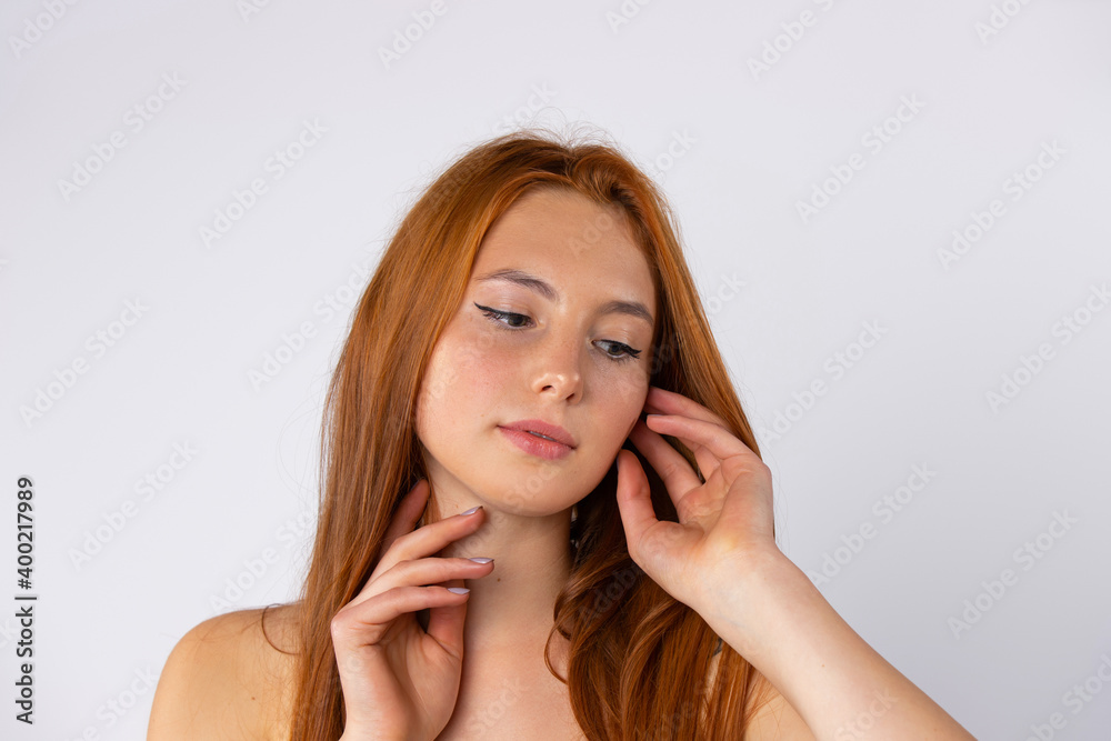 Beauty, spa and glowing skin concept. The red-haired girl poses and looks at the floor on white background. Beauty, spa and glowing skin concept. The red-haired girl poses and looks at the floor on white background.