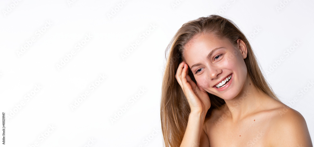 Smiling blonde on a white background straightens her long hair. Empty space. Skinimalism and natural skin texture