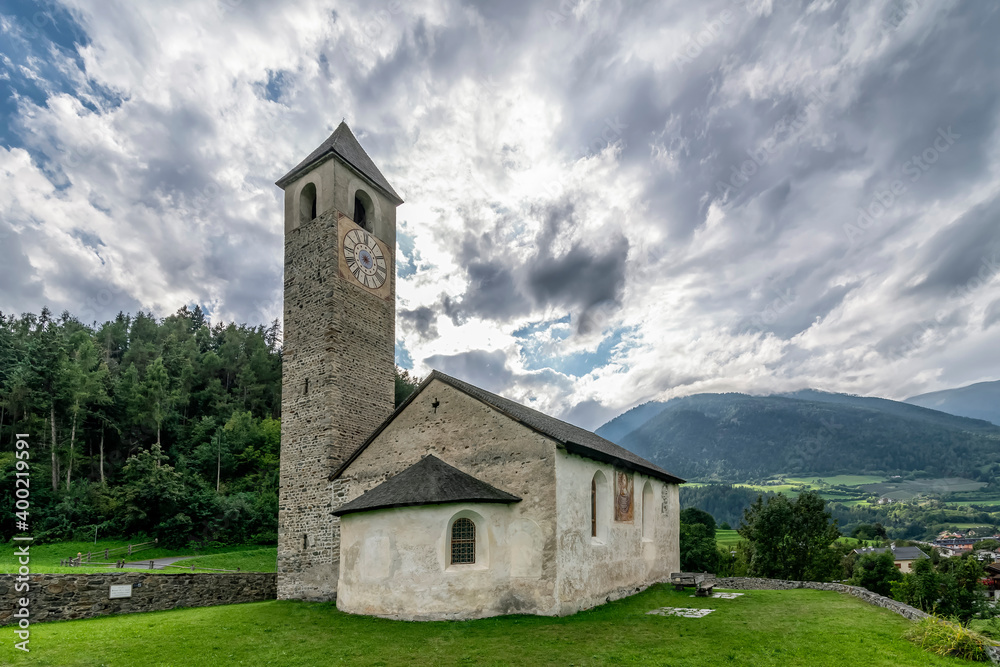 The ancient Church of San Giovanni in Prato allo Stelvio, South Tyrol, Italy, under a dramatic sky