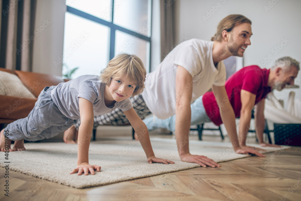 Two men and their son standing in plank