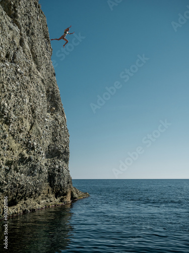 Girl jumps into the sea from a very high rock