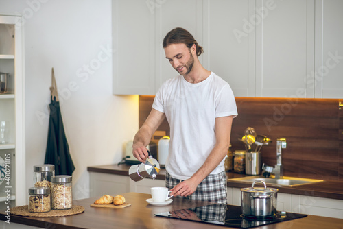 Young man in homewear preparing breakfast in the kitchen